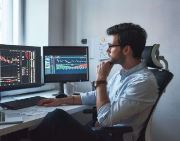 businessman in formal wear and eyeglasses working with charts on computer in his office