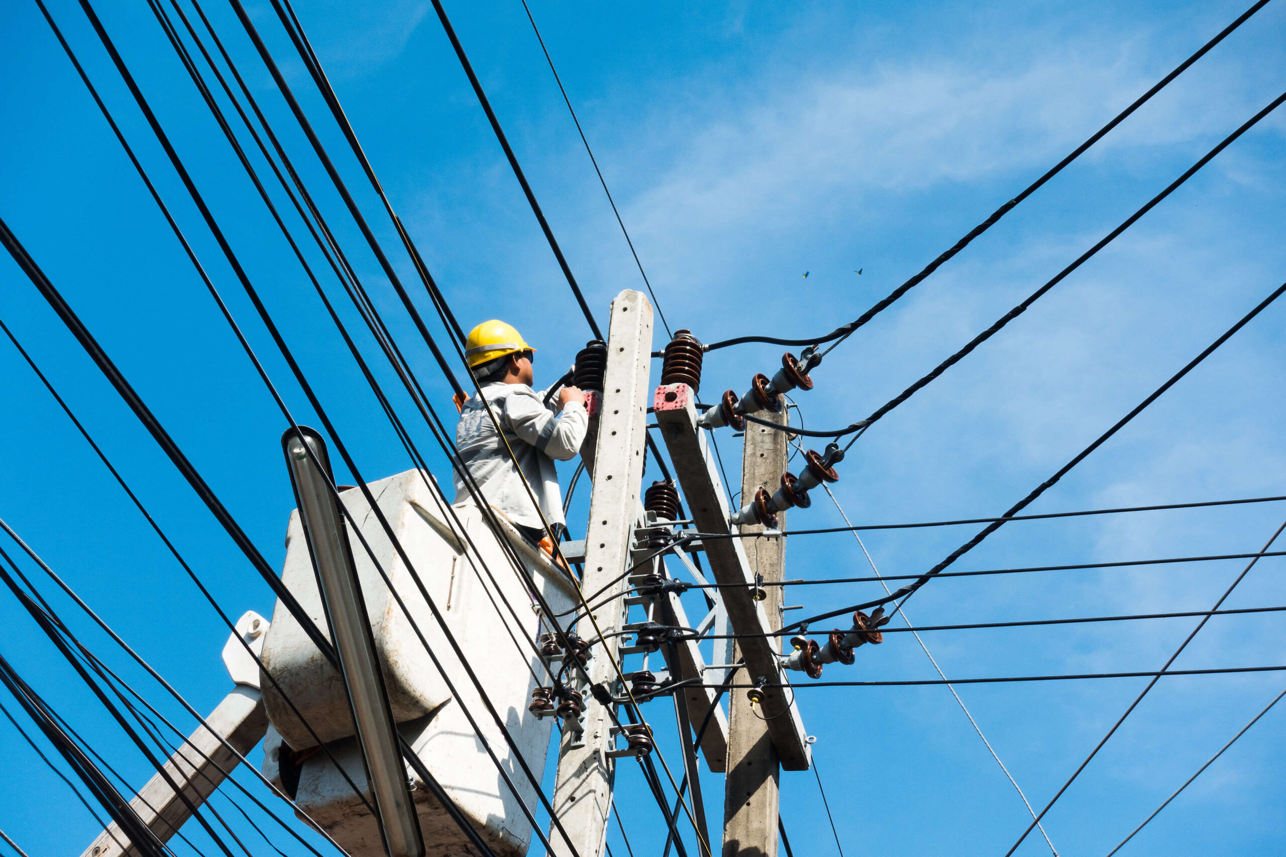 electricians repairing wire of the power line on electric power pole on crane