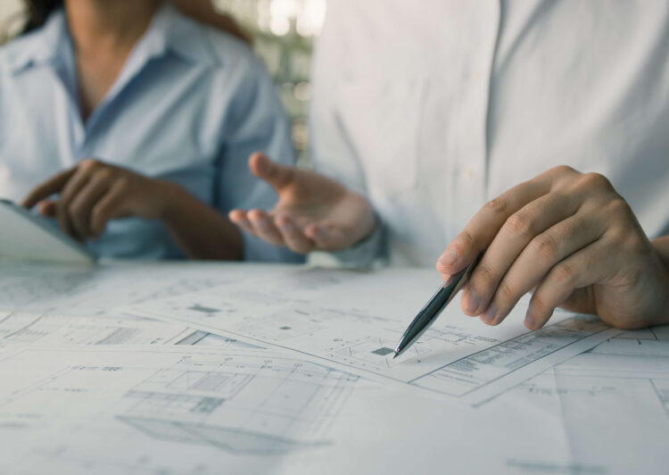 engineer working with blueprints on table and discussing project