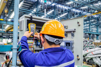 Electrician engineer repairing control panel with voltage meter